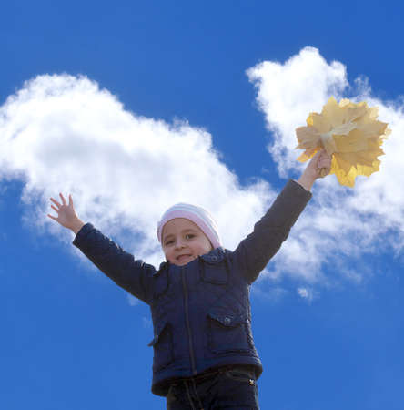 Little happy girl with autumn bouquet yellow dry leavesの写真素材