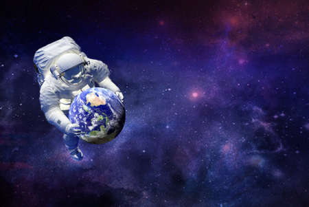 traveling by galaxy spaceman witch planet earth in hands.の写真素材