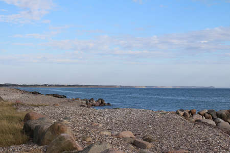 Stone beach on the North Sea. The coast along the ocean is sandy. The area is rocky green. The sky...