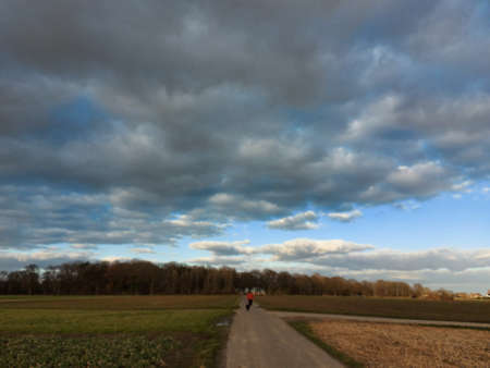 A man running on a country road with dark clouds in the skyの写真素材