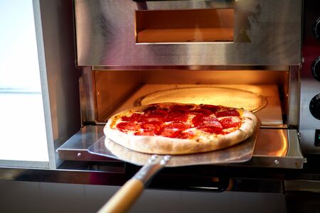 baker puts pizza in the ovenの写真素材