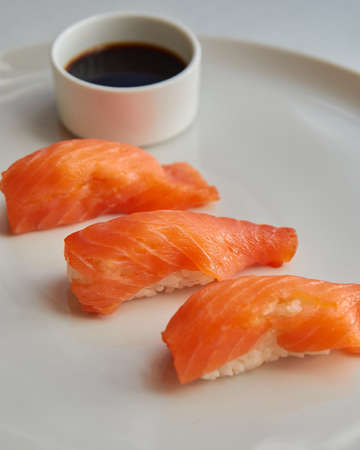 Sushi rolls. Japanese food in the restaurant. Sushi with salmon and soy sauce on a white plateの写真素材