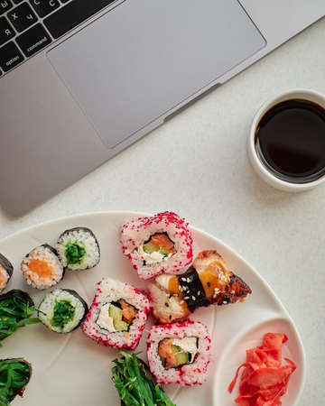 Food delivery. Tasty sushi rolls at workplace closeup