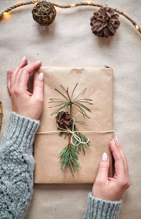 The hands of a young woman create and pack Christmas and New Year presents for the holiday. Presents to relatives and friends with congratulationsの写真素材