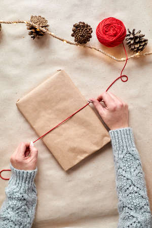 The hands of a young woman create and pack Christmas and New Year presents for the holiday. Presents to relatives and friends with congratulationsの写真素材