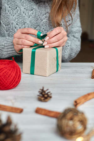 The hands of a young woman create and pack Christmas and New Year presents for the holiday. Presents...