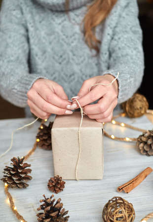 The hands of a young woman create and pack Christmas and New Year presents for the holiday. Presents to relatives and friends with congratulationsの写真素材