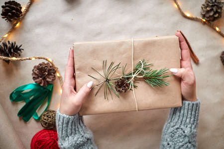 The hands of a young woman create and pack Christmas and New Year presents for the holiday. Presents to relatives and friends with congratulationsの写真素材