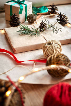 Christmas gifts on the background of a red woolen checkered plaid with garlands of cones and fir branches, a beautiful still lifeの写真素材