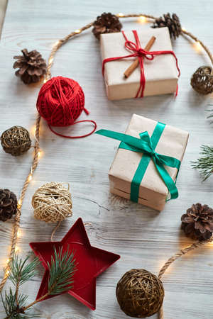 Christmas gifts on the background of a red woolen checkered plaid with garlands of cones and fir branches, a beautiful still lifeの写真素材