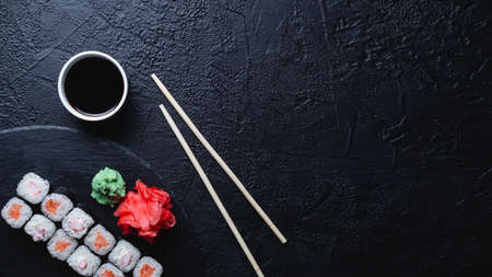 Sushi rolls with salmon, rice, eel and soy sauce on dark stone background, space for text, large bannerの写真素材