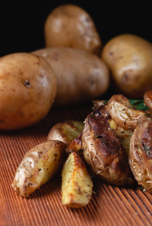 Delicious baked country potatoes with spices, dill and green onions, on a wooden tableの写真素材