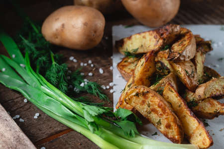 Delicious baked country potatoes with spices, dill and green onions, on a wooden tableの写真素材