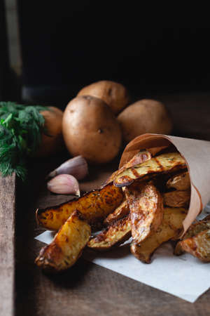 Delicious baked country potatoes with spices, dill and green onions, on a wooden tableの写真素材