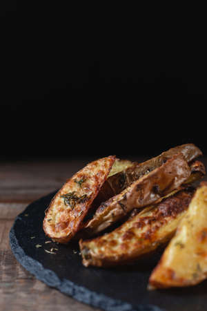 Delicious baked country potatoes on a slate cutting stone on a wooden tableの写真素材