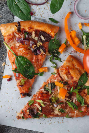 Homemade Italian pizza with bell peppers, tomatoes, cheese, onions and herbs, on light baking paperの写真素材