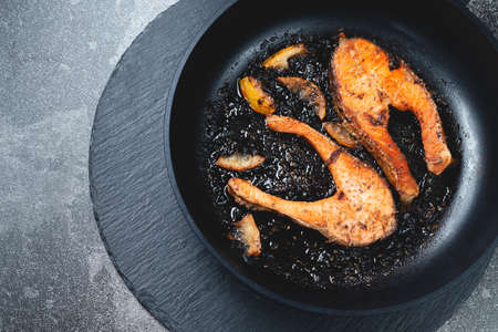 Juicy pan fried salmon steak on a natural slate stone table, close-up. Deliciously cooked salmon fillet. Flat-lay, top viewの写真素材