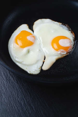 fried eggs in a black frying pan, close-upの写真素材