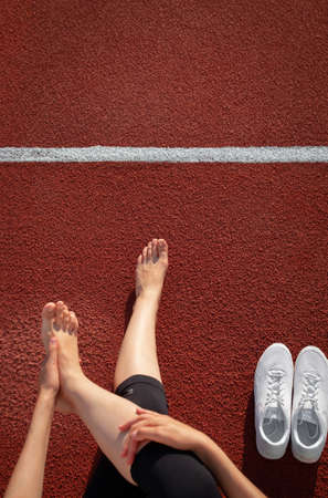 Banner women's legs. A woman's hand tying the laces on her sneakers at the stadium. Preparing to run. Space for text. Top view. Verticalの写真素材