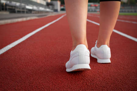 Young athletic girl leg in white sneakers runner getting ready for a productive fitness workout marathonの写真素材