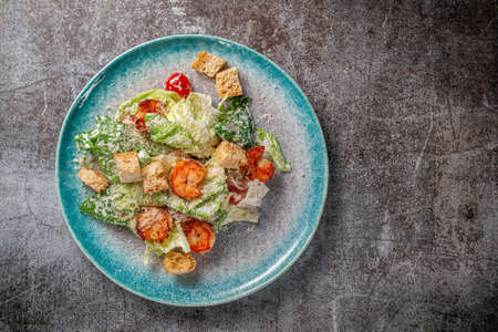 Healthy salad with fried shrimp, greens and croutons in a plate against a gray stone table. A healthy breakfast in a restaurantの写真素材
