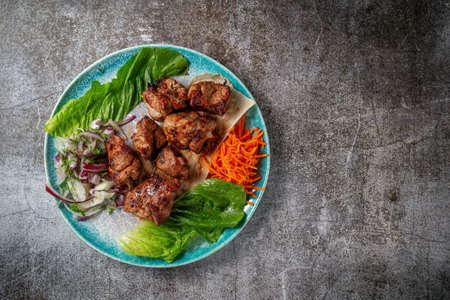 Serving a dish from the restaurant menu. Grilled beef and pork meat with grated carrots and herbs on a plate against a gray stone table, delicious kebabの写真素材