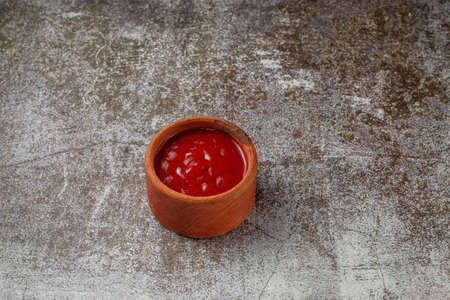 Tomato sauce in a sauce pot on a restaurant stone tableの写真素材