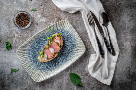 Open bacon and radish sandwich on a gray stone tableの写真素材