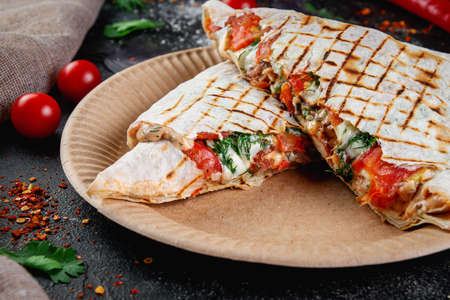 Shawarma, pita pie, stuffed with chicken, beef and herbs on a dark stone table. Fast food and...