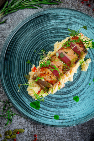 Fried tuna fillet with couscous and herbs on a gray stone tableの写真素材