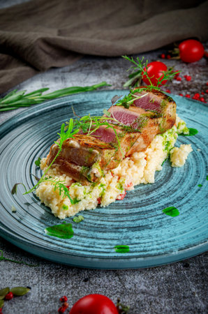 Fried tuna fillet with couscous and herbs on a gray stone tableの写真素材