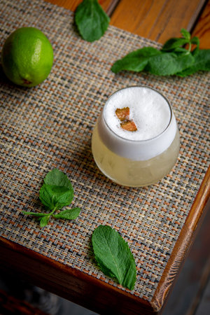 Alcoholic Peruvian cocktail. Pisco Sour cocktail with ingredients with lemon on wooden background.の写真素材