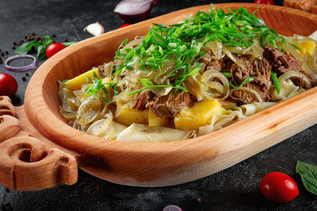 Traditional Kazakh dish Beshbarmak. Aromatic roast of lamb and beef with lots of onions and vegetables in a wooden dish Astauの写真素材