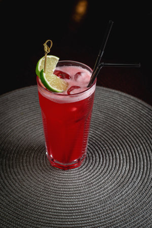 Red Campari cocktail with lime in a glass tumbler and drinking tube, bar cocktail in a restaurantの写真素材