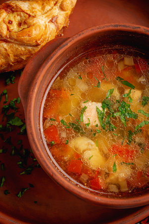 Hot chicken soup in an earthenware bowl, top viewの写真素材