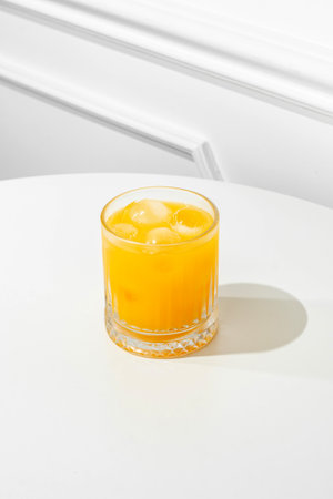 Orange juice in a glass on a white table, sunny hard light.の写真素材