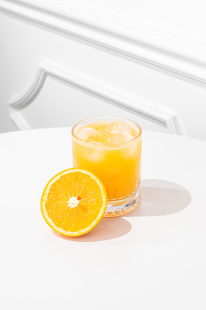 Orange juice in a glass on a white table, sunny hard light.の写真素材