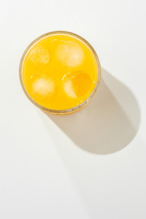 Orange juice in a glass on a white table, sunny hard light.の写真素材