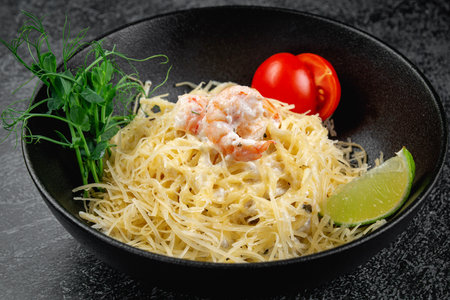 Pasta carbonara with shrimp in dark plateの写真素材