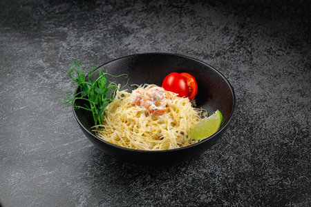 Pasta carbonara with shrimp in dark plateの写真素材