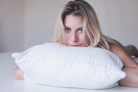 blonde girl laying on white pillowの写真素材
