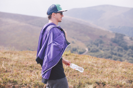 boy walking down the mountain with a bottle of water in handの写真素材
