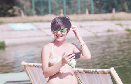 girl is taking self portrait on the lake beachの写真素材