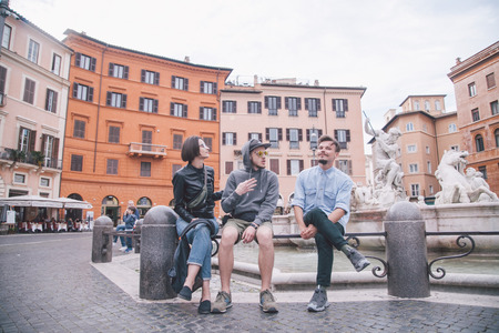 three friends chatting on fountain in Romeの写真素材