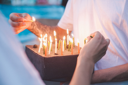 Friends are lighting candles on a birthday cakeの写真素材