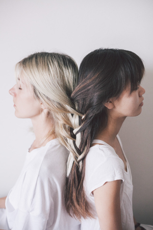 blonde girl and brunette girl with their hair braided togetherの写真素材