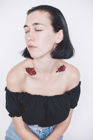 portrait of girl with closed eyes and leaves on shouldersの写真素材