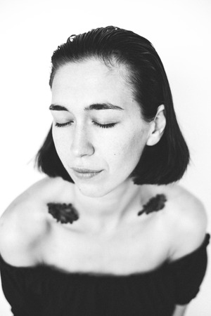 portrait of girl with closed eyes and leaves on shouldersの写真素材
