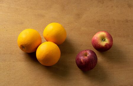 Three oranges and two apples on wooden tableの写真素材