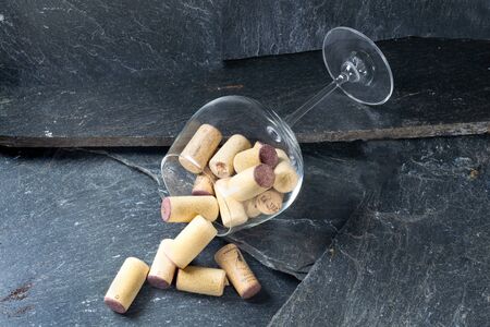 Wine glass filled with corks on dark gray stoneの写真素材